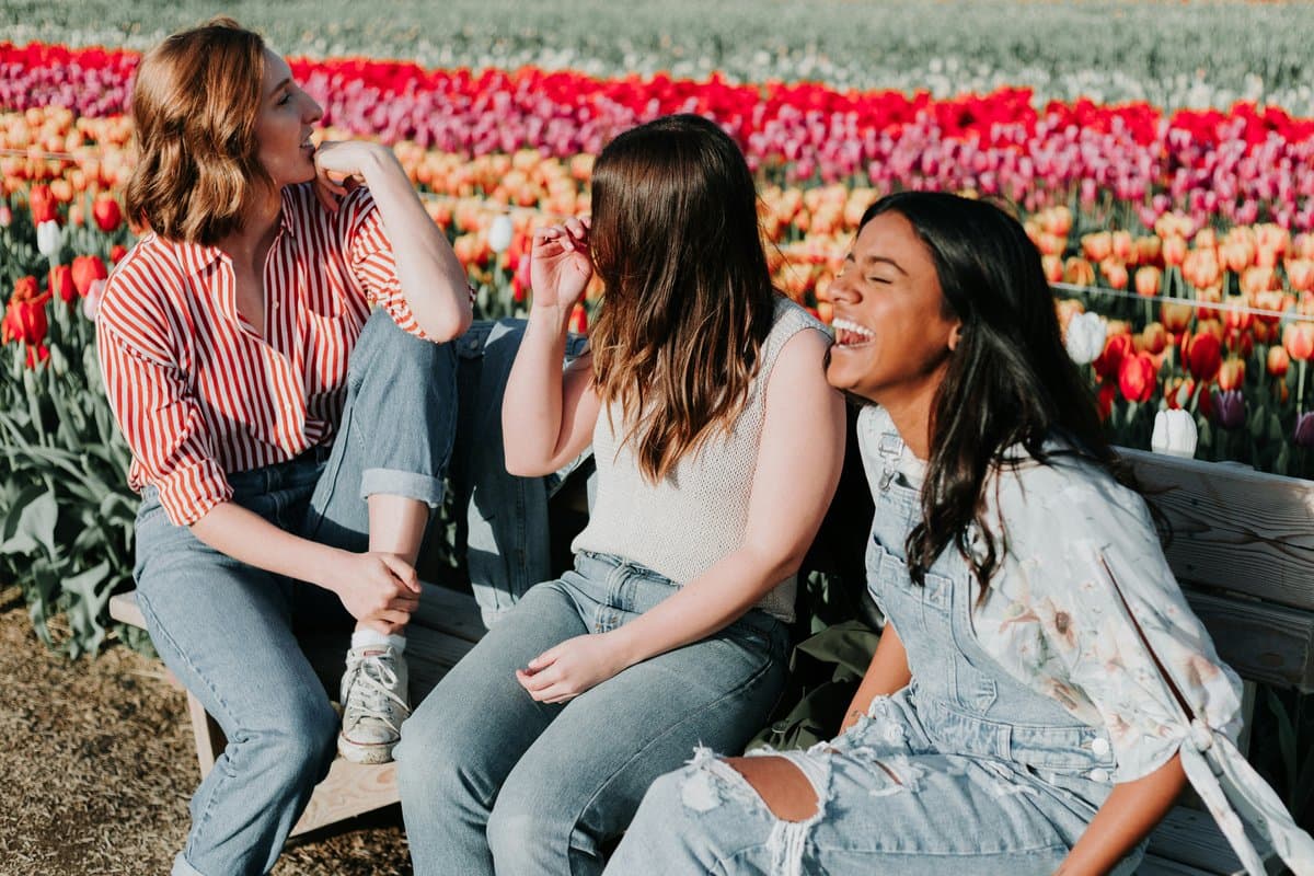 Three friends laughing in a tulip field